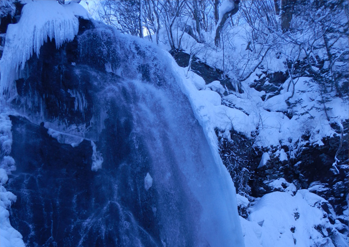 Winter activity example: Blue Falls Tour. A sparkling blue frozen waterfall.